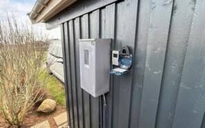 A utility box mounted on a gray wooden wall, with a small, rectangular device attached to it. - 4 Star Holiday Home in Hejls (Hejls)