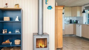 A modern kitchen with a wood-burning stove, wooden cabinets, and a tiled floor. - 4 Star Holiday Home in Hejls (Hejls)