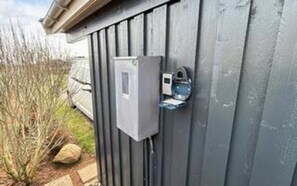 A utility box mounted on a gray wooden wall, with a small, rectangular device attached to it. - 4 Star Holiday Home in Hejls (Hejls)