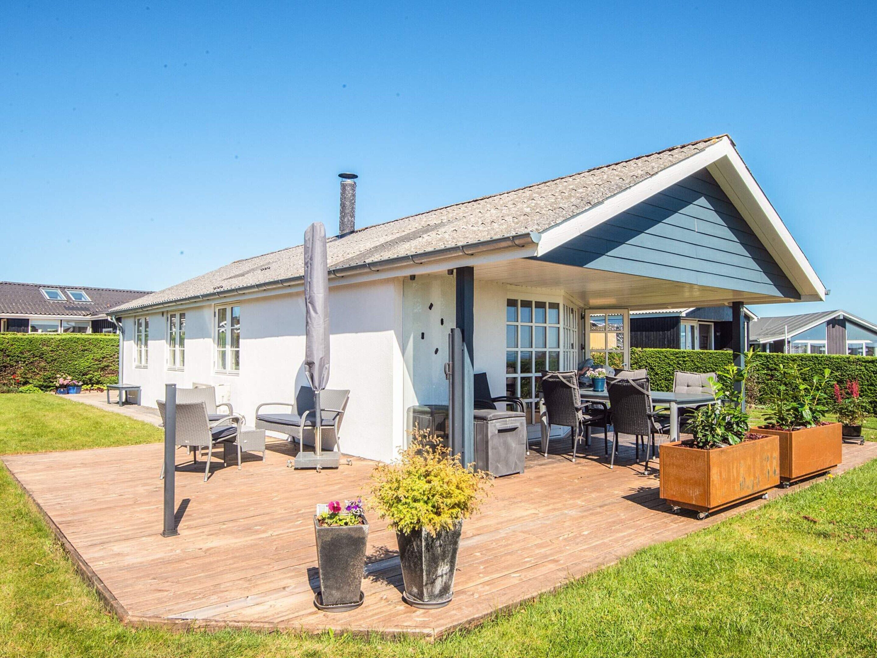 A modern house with a covered patio, outdoor furniture, and a garden area.