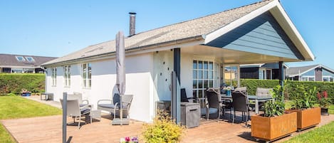 A modern house with a covered patio, outdoor furniture, and a garden area.