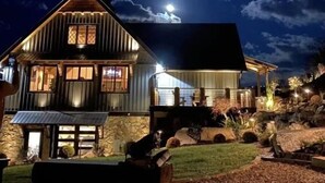 Ein zweistöckiges Holzhaus mit Stein Fundament, einer Veranda und einer gut beleuchteten Fassade.