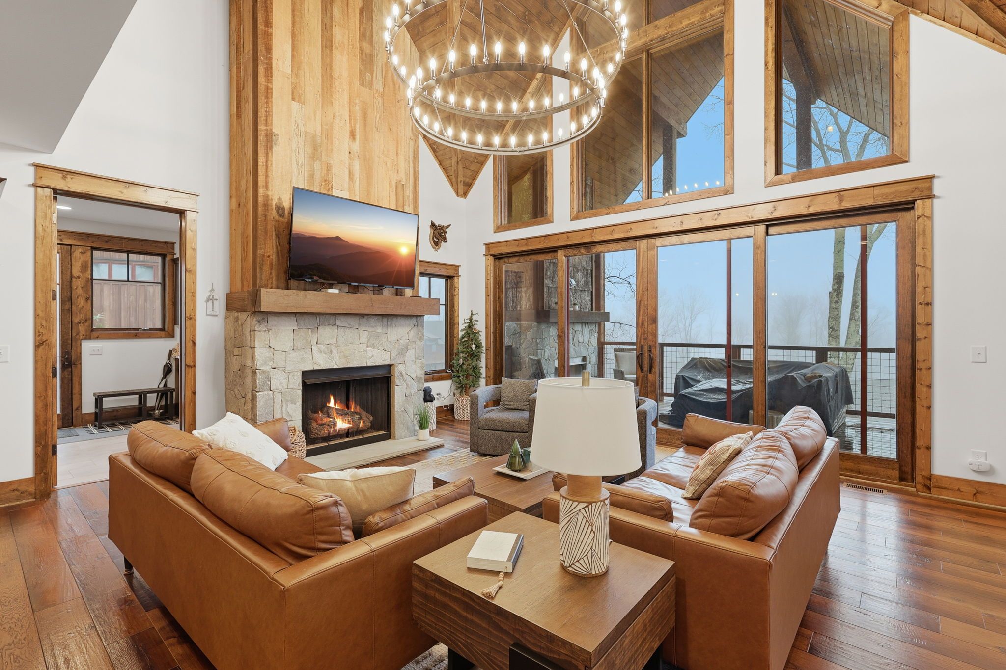 Ein großzügiges Wohnzimmer mit Kamin, Ledersofas, einem großen Fernseher und einer Kristallleuchter.