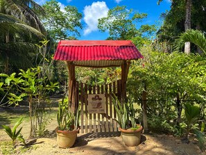 A wooden structure with a red roof, surrounded by potted plants and a fence.