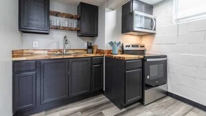 A modern kitchen with dark cabinets, a wooden countertop, a built-in microwave, and a stainless steel oven. - Modern Midtown Getaway! Central location for 12! (Omaha)