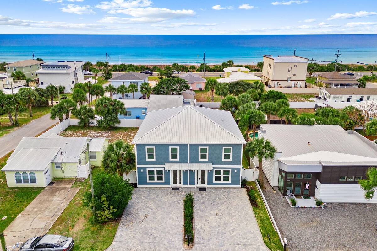 A residential area with houses, a paved driveway, and a view of the ocean.