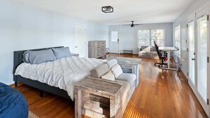 A bedroom with a large bed, a wooden coffee table, a sofa, and a desk with a chair.