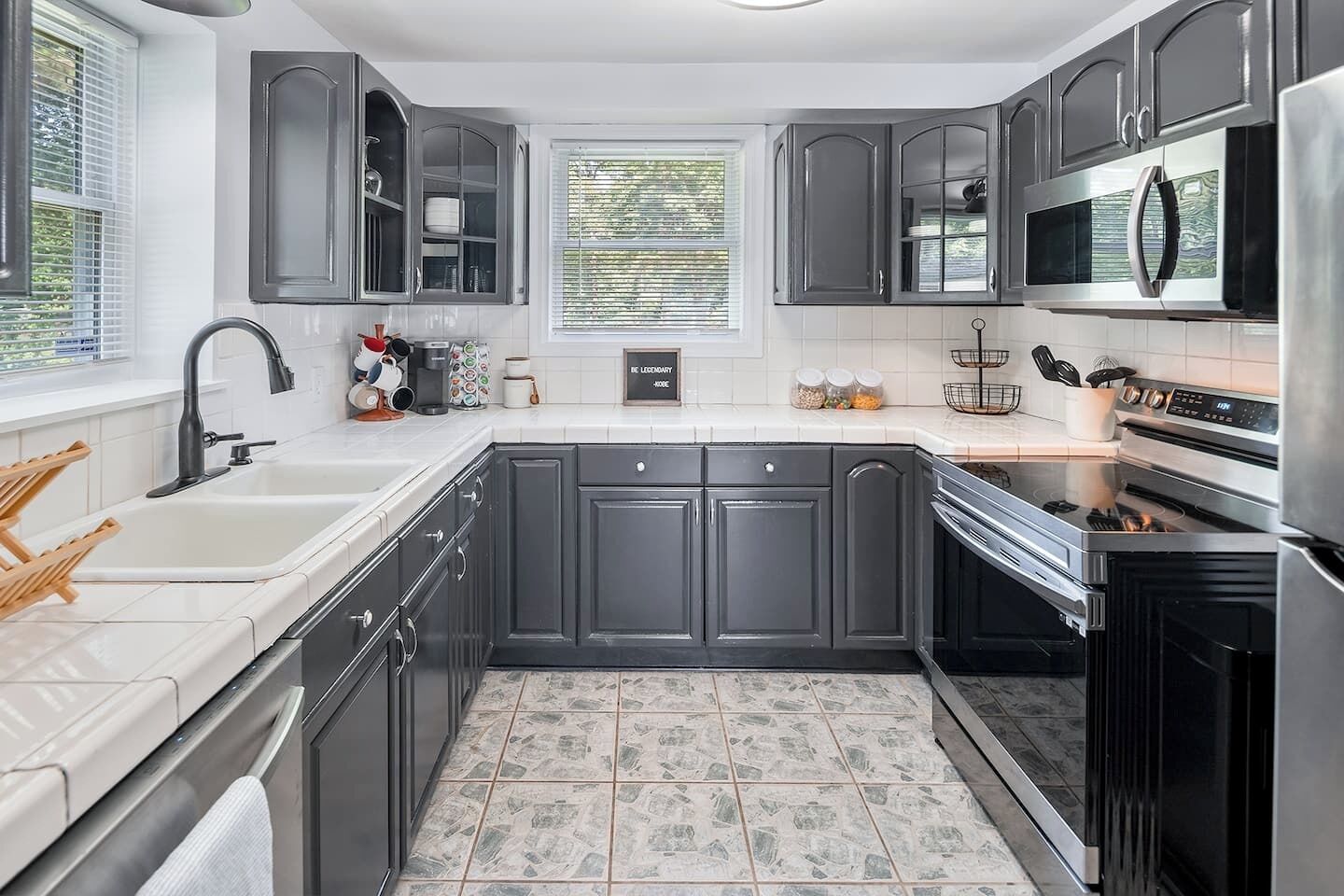 A modern kitchen with dark cabinets, stainless steel appliances, and a tiled backsplash.