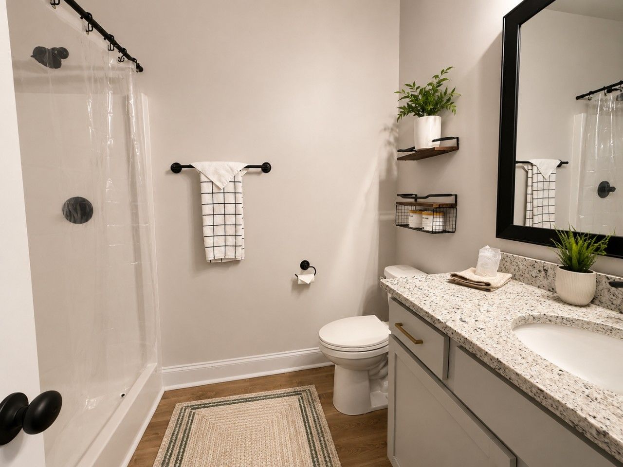 A bathroom with a shower, toilet, sink, and mirror.