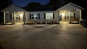 A two-story building with a garage, illuminated windows, and a driveway.