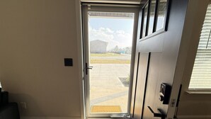 A room with a door leading to a driveway, a welcome mat, and a window with blinds.