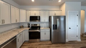 A modern kitchen with white cabinets, stainless steel appliances, and a granite countertop.