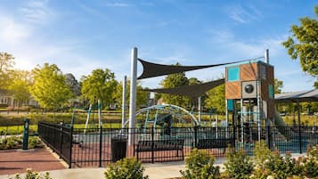 A playground with a climbing structure, a shaded area, and a fenced play area.