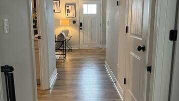 A hallway with wooden flooring, white walls, and doors with black handles.