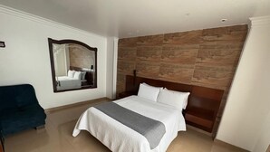 Una camera da letto con un letto, uno specchio, una sedia blu e una testiera in legno.
