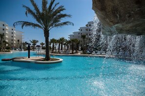Ein Pool mit Palmen, Liegestühlen und einer Felsformation.