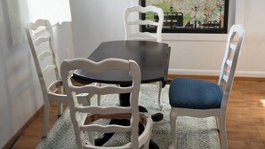 Ruokailutilassa on pöytä ja neljä tuolia, matto ja seinällä oleva kehystetty kartta.
