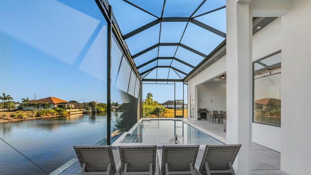 Et moderne poolområde indendørs med glasvægge, liggestole og frit udsyn til det omkringliggende landskab.