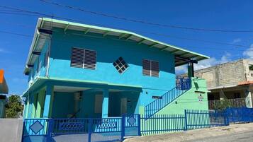 A two-story building with a blue exterior, a covered front porch, and a staircase leading to the upper floor.