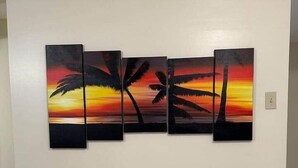 Pared con una obra de arte de tres paneles que muestra palmeras al atardecer.