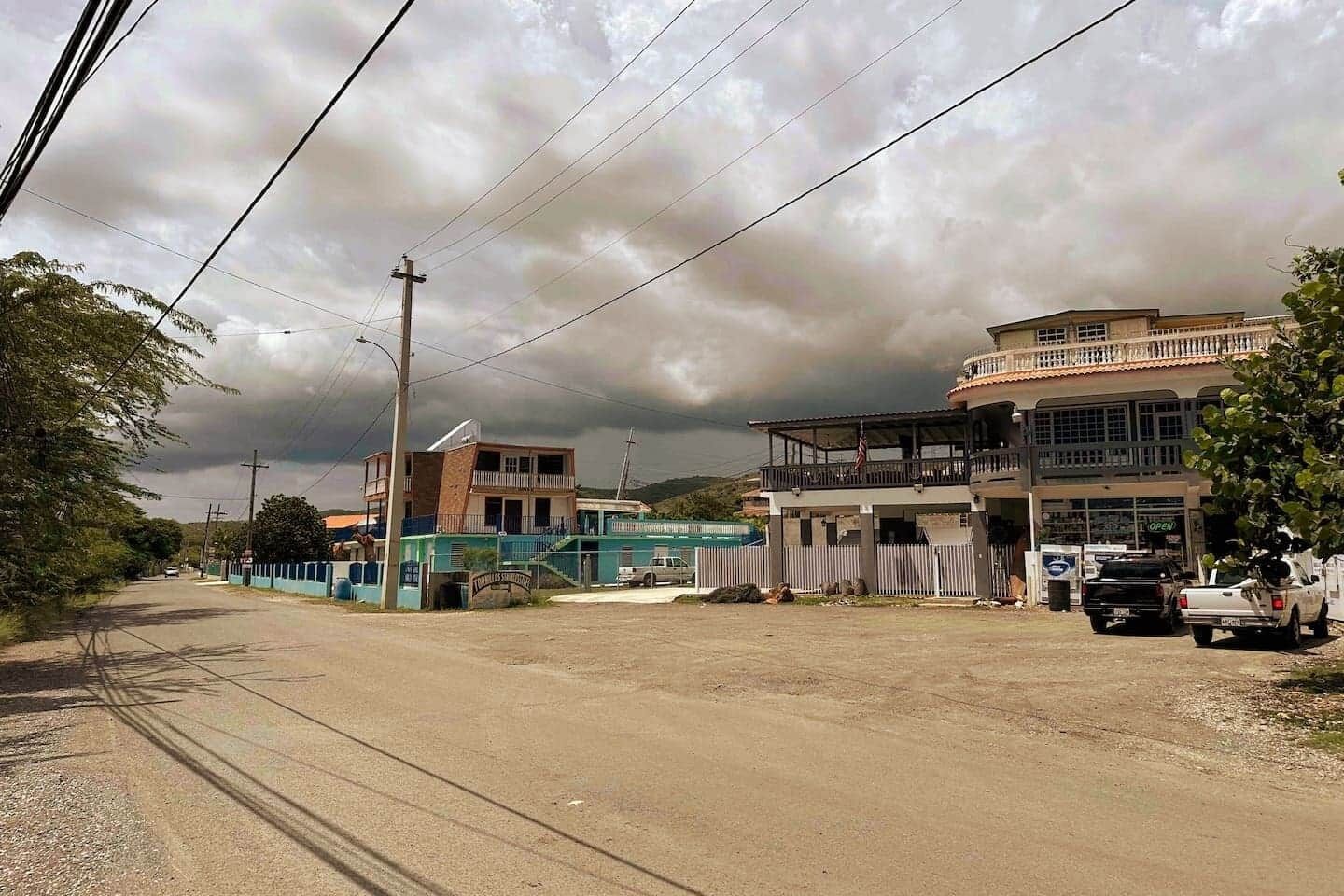 A two-story building with a balcony, a sign that reads "OPEN," and a truck parked in front.