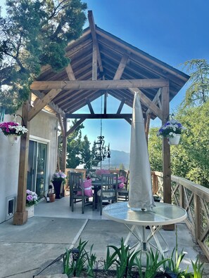 Un patio techado al aire libre con una pérgola de madera, una mesa con sillas y una fuente decorativa.
