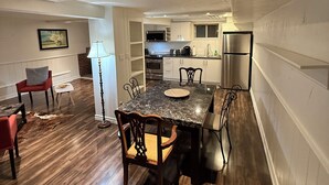 A spacious living area with a dining table, chairs, and a red armchair. A kitchen is visible in the background with modern appliances. - Spacious 2BR Basement • Full Kitchen • Vaughan (Vaughan)