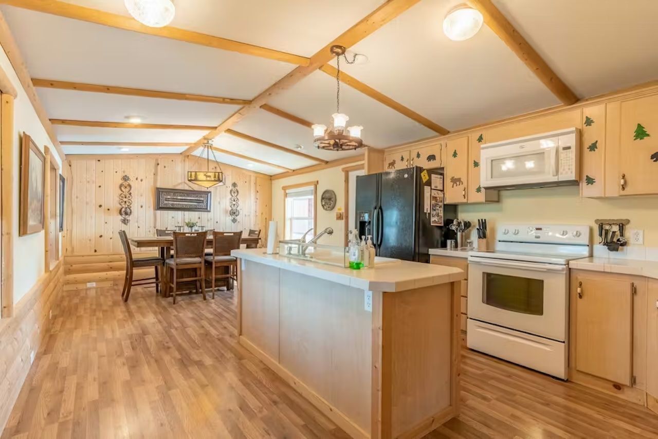 Una cocina con armarios de madera, una isla central con un fregadero, un refrigerador y un horno.