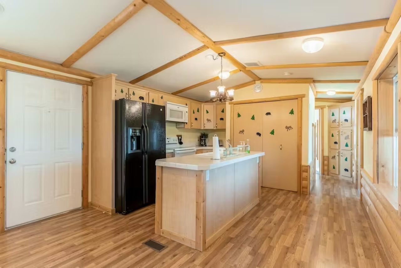 Una cocina con armarios de madera, un refrigerador negro, un microondas y una isla de madera.