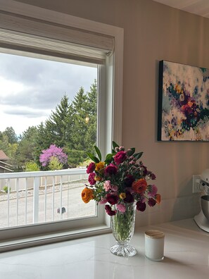 A kitchen with a large window, a vase of flowers, and a painting on the wall. - Charming house in lovely Spokane south hill, perfect for your next getaway! (Spokane)