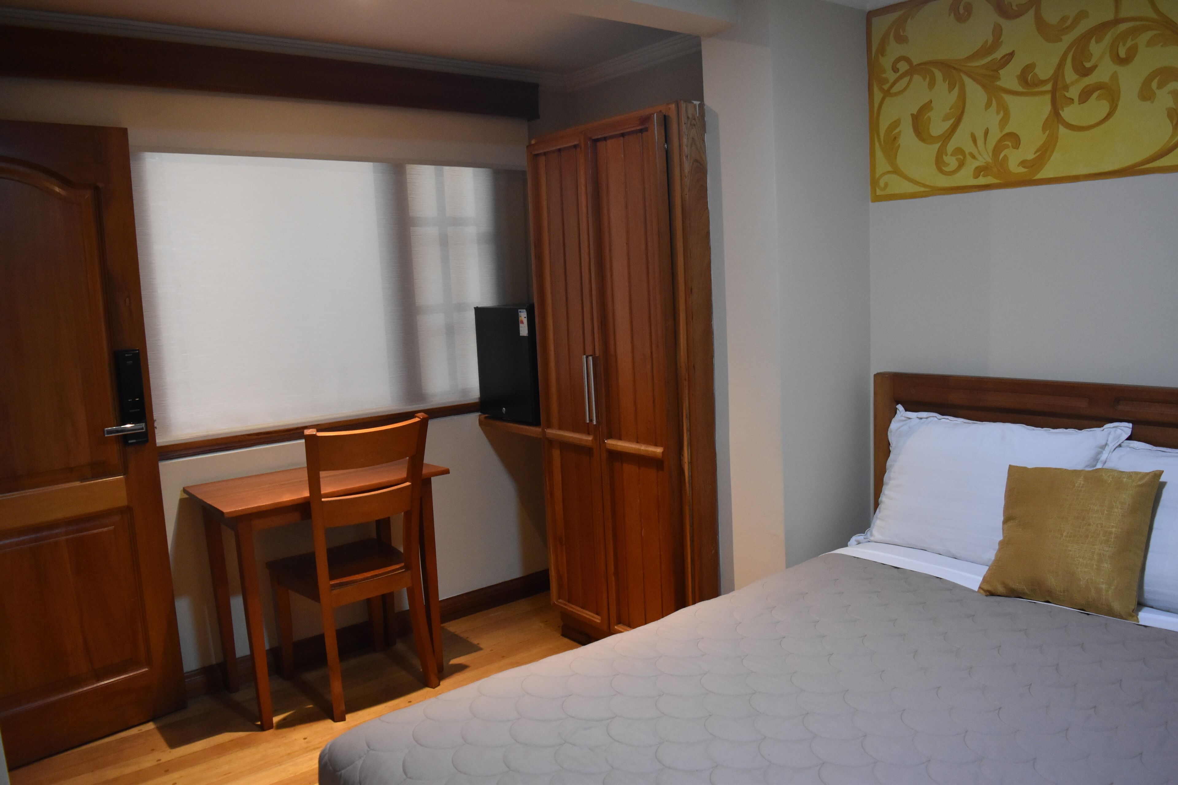 A bedroom with a bed, a desk, and a wardrobe.