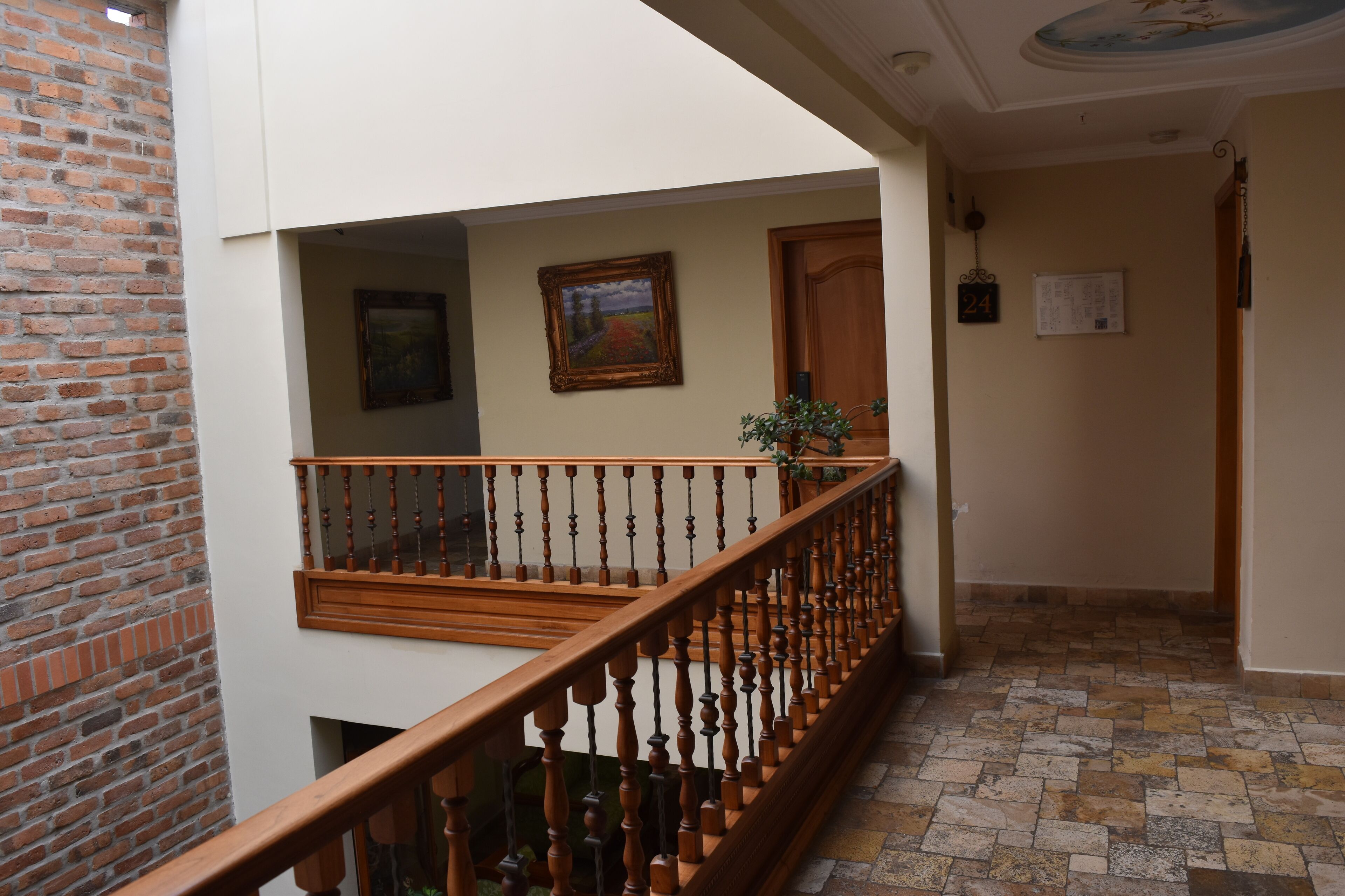 A staircase with wooden balusters, a brick wall, and a tiled floor.