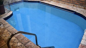 Ein Schwimmbecken mit einer Fliesenkante und einer Metallleiter.