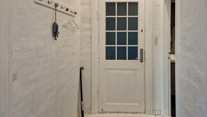 A white door with a grid pattern window, a coat hook with a decorative item, and a wall-mounted light switch. - 2 bedroom nice apartment in Skagen (Skagen)