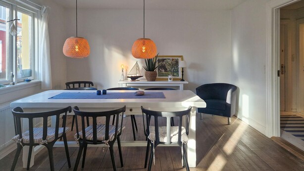 A dining area with a white table, black chairs, and two orange pendant lights. - 2 bedroom nice apartment in Skagen (Skagen)