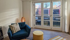 A living room with a blue armchair, a small round ottoman, and a wicker lamp. - 2 bedroom nice apartment in Skagen (Skagen)