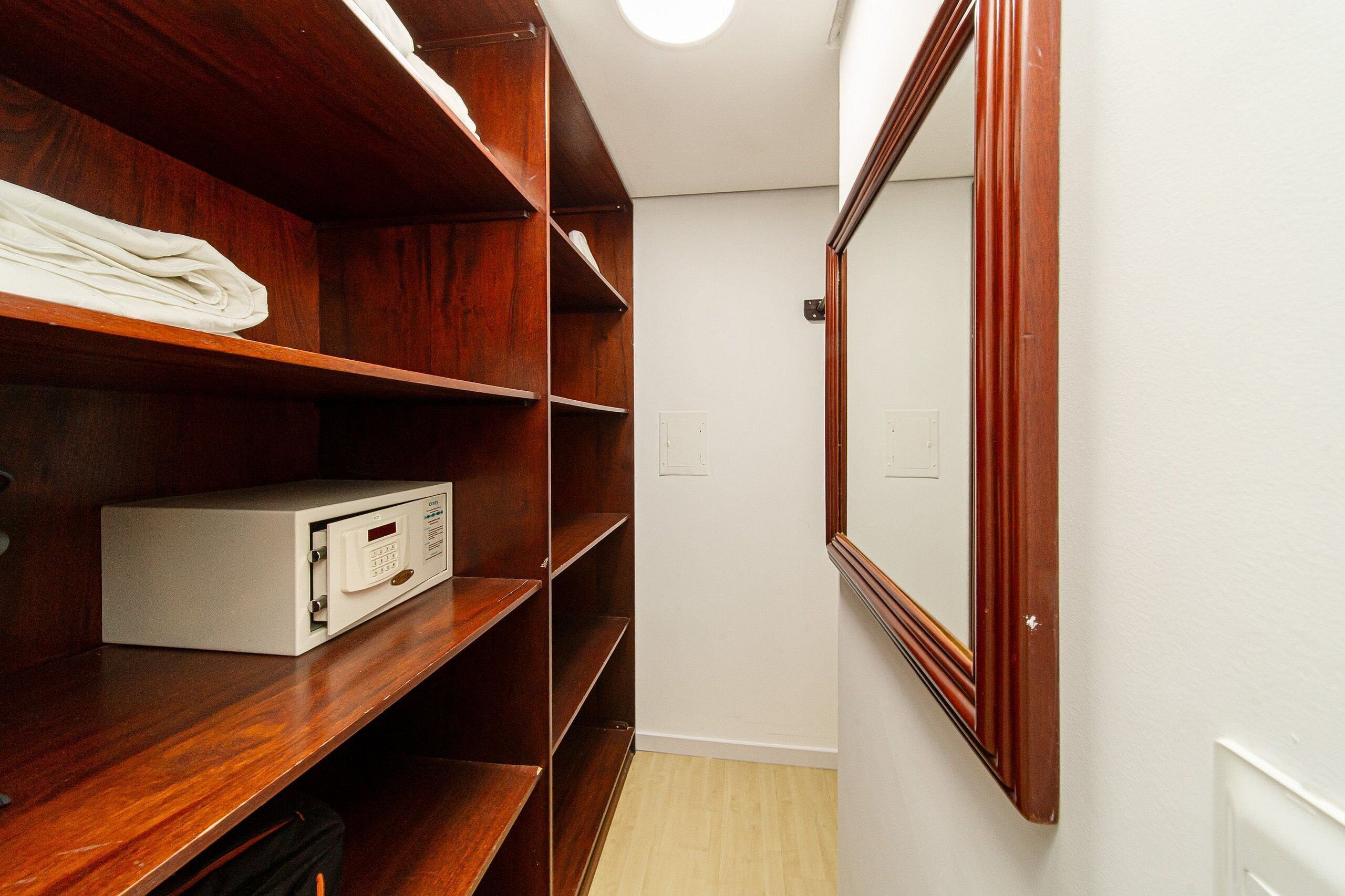 A walk-in closet with wooden shelves, a mirror, and a white storage unit.