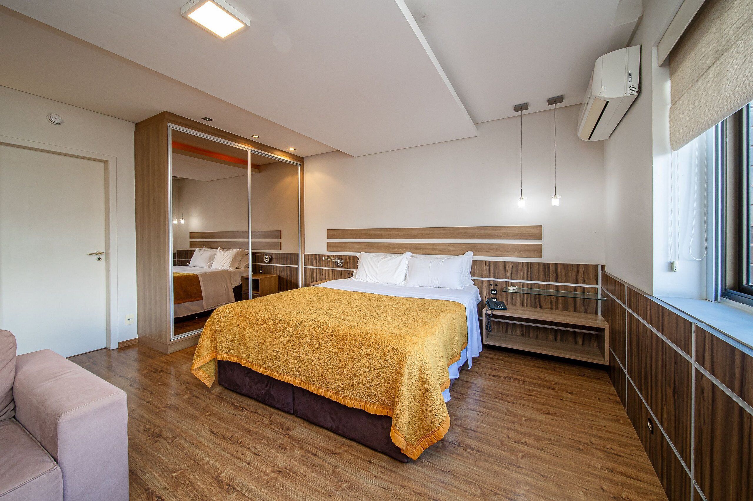 Une chambre d’hôtel moderne dotée d’un grand lit, d’une armoire, d’un coin salon et d’une fenêtre offrant une vue agréable.