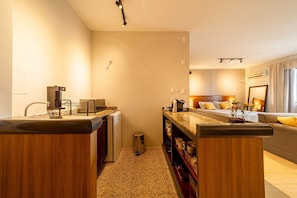 A modern hotel room with a kitchenette, a bed with yellow pillows, and a small bathroom. - Hotel Prinz (Joinville)