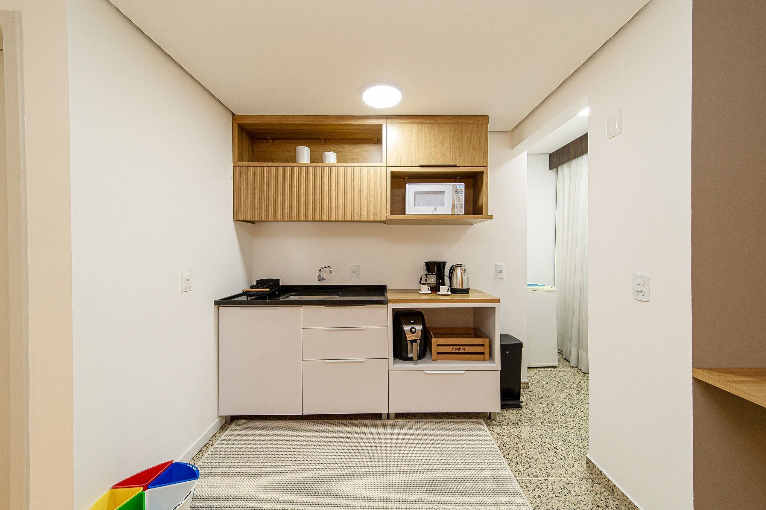 A compact kitchen with a microwave, coffee maker, and a sink.