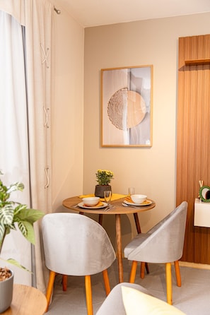 A dining area with a round table, two grey chairs, a potted plant, and a framed artwork on the wall. - Hotel Prinz (Joinville)