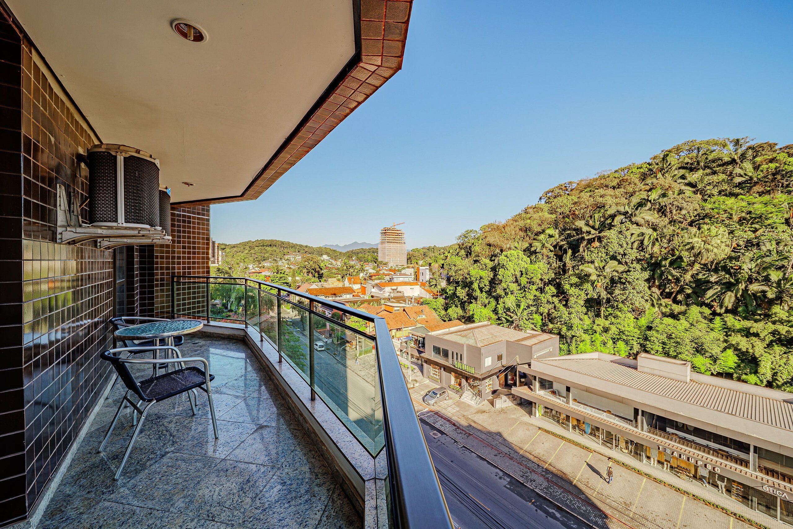 A balcony with a glass railing, a table, and two chairs.