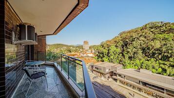A balcony with a glass railing, a table, and two chairs.