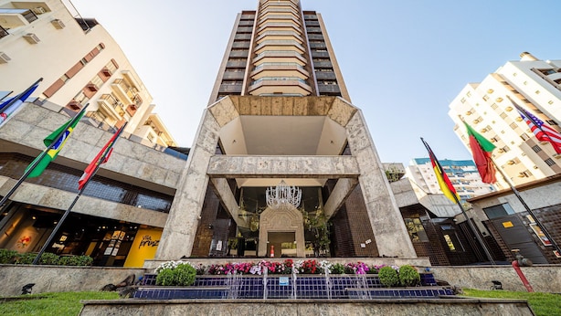 Un edificio alto con una entrada central, varios balcones y banderas.
