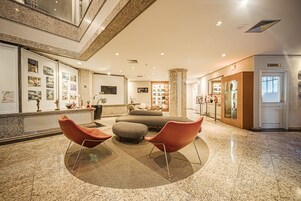 Um hall de entrada com balcão de recepção, área de estar e um grande pilar.
