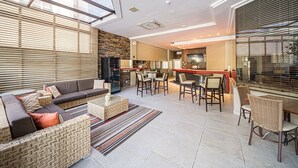 Un amplio salón con sofá, sillas, una mesa de centro y una cocina con mostrador y sillas.