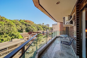 A balcony with a glass railing, a table, and two chairs. - Hotel Prinz (Joinville)