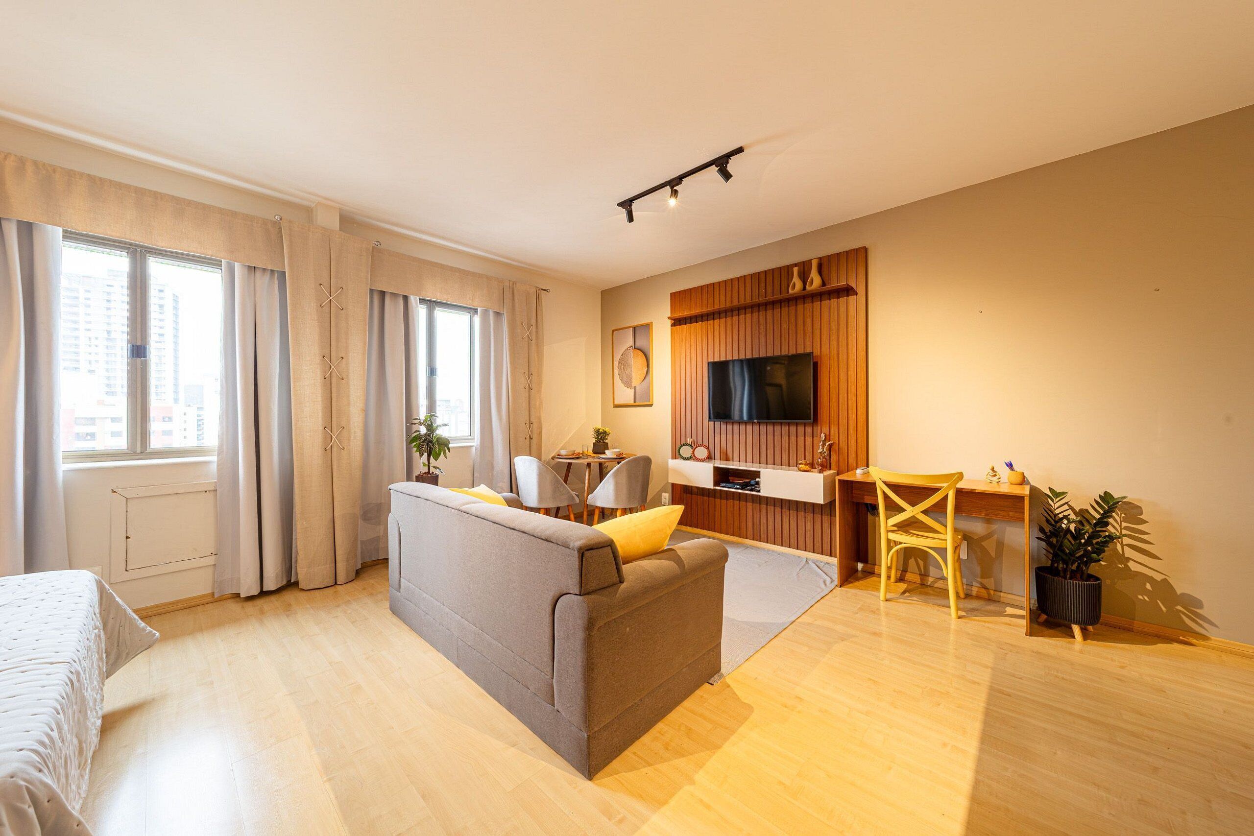 A modern living room with a sofa, a dining table, a TV, and a plant.