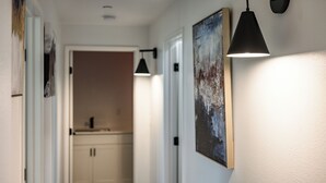 Ein Flur mit einer modernen Leuchte und einem gerahmten Kunstwerk an der Wand.