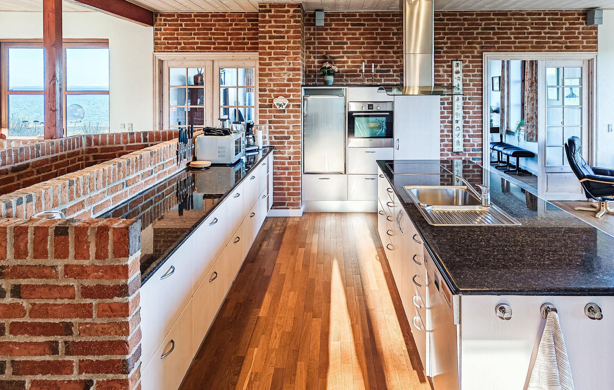 Una cocina moderna con paredes de ladrillo, suelo de madera y electrodomésticos de acero inoxidable.